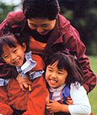 Picture of a mother with two young girls hugging and laughing.
