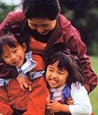 Picture of a mother with two young girls hugging and laughing.
