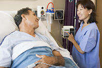 Picture of a female nurse helping a male patient in a hospital bed.
